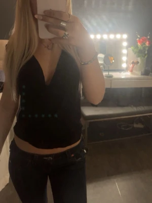 Svart omlott linnetopp - Snygg svart omlott linnetopp med djup v-ringning och croppad passform. Toppen är ärmlös och har en stilren look. Använt fåtal gånger!