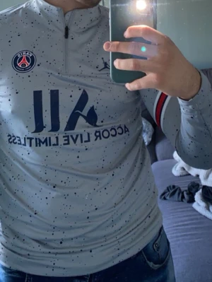 Psg tröja  - Bilden visar en långärmad träningströja från PSG med prickigt mönster och dragkedja vid halsen, inte en sko.