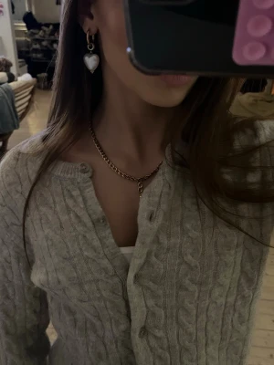 Beige kabelstickad kofta - Supermysig beige kabelstickad kofta med knappar framtill. Koftan har lång ärm och ribbade muddar vid ärmslut och nederkant. Den är originellt köpt ifrån H&M 💞