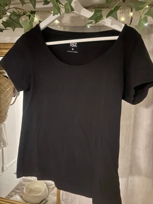 Svart basic t-shirt från 157 - En svart enkel t-shirt från 157 med rund halsringning och korta ärmar. Tillverkad i mjuk bomull med lite stretch för en bekväm passform. Perfekt att styla till jeans eller kjol för en clean look.