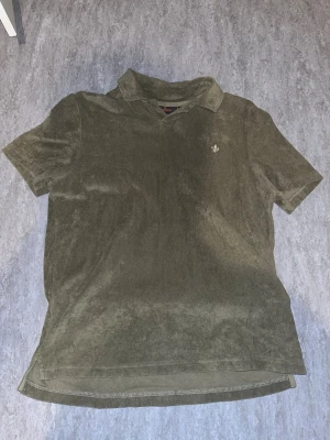 Olivgrön frottéskjorta från Morris XS - Säljer en olivgrön skjorta från Morris i mjuk frotté. Skjortan har korta ärmar, klassisk krage och en liten broderad logga på bröstet. Köptes för 900kr org  och har endast använts ungefär 4 gånger