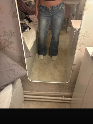 Lågmidjade vintage jeans från rock&roll - Säljer ett par blå bootcut jeans från Rock & Roll med låg midja. Jeansen har snygga slitningar, broderade detaljer. Köpte från A2V men har knappt använt efter så de är fortfarande i jättebra skick💕