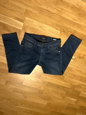 Replay Anbass mörkblå jeans - Snygga mörkblå Replay Anbass jeans. Jeansen har en midwaist och är tillverkade i stretchigt bomullsmaterial för extra komfort. Perfekt för dig som gillar en modern och stilren look. St w30 L 34 