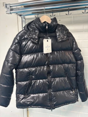 Svart pufferjacka från Moncler L - Säljer en svart pufferjacka från Moncler i storlek L. (Moncler Maya) helt ny. Pris kan diskuteras. Öppen för frågor