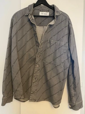 Grå overshirt från Axel Arigato - Säljer denna väldigt varsamt använda overshirt från axel arigato. Det står storlek S men sitter snarare som L.