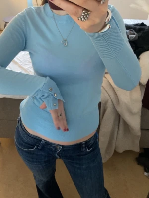 Ljusblå långärmad tröja - Jättesöt ljusblå långärmad tröja med silvriga knappar och detaljer. Tröjan är ribbad nertill och i ärmarna vilket gör att den sitter extra fint🥰Storlek XS men jag har vanligtvis S och den passar mig bra 