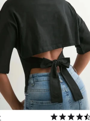 Svart croppad topp med knyt i ryggen - Säljer en svart croppad topp med halvlånga ärmar och öppen rygg som knyts med en stor rosett baktill. 