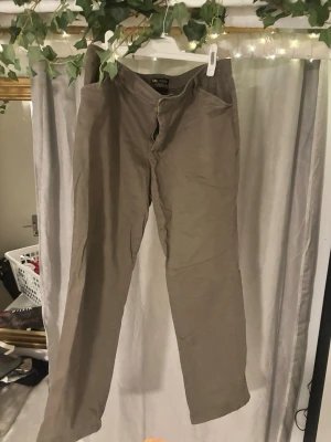 Beige straight leg byxor från Lee - Snygga beige byxor från Lee med relaxed fit och straight leg. Midwaist-modell som sitter skönt och har klassisk look. Tillverkade i 98% bomull och 2% elastan för lite stretch. Perfekta för dig som gillar enkel och stilren design.