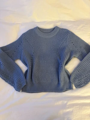 Blå stickad tröja  - Snygg blå stickad tröja med rund hals och långärmade ärmar. Tröjan har ett coolt strukturerat mönster och breda muddar vid ärmslut och nederkant. 