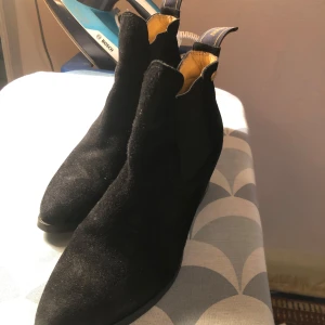 Svarta Chelsea boots från Novita - Snygga svarta Chelsea boots i mocka från Novita. De har en klassisk design med elastiska paneler på sidorna och en liten klack. Perfekta för både vardag och mer uppklädda tillfällen.