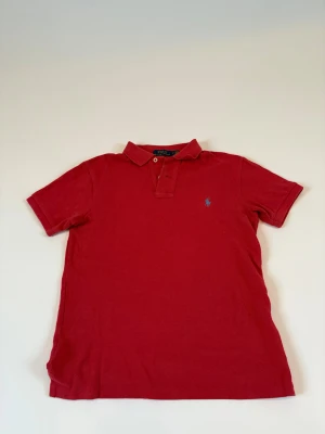  Ralph Lauren pike - Snygg röd pikétröja från Polo Ralph Lauren med klassisk krage och två knappar framtill. Hör av dig vid frågor. Den sitter som XS