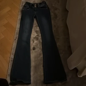 Bootcut jeans från Girl Vivi, mörkblå -  Skulle nog säga att de passar om du är mellan 160-167💖Snygga mörkblå bootcut jeans från Girl Vivi med lågmidjad passform och coola guldfärgade knappar framtill. Jeansen har klassiska fickor bak och fram, samt detaljerad sömnad vid midjan. Perfekt för dig som gillar lågmidjade jeans. Tyvärr för långa för mig.💖