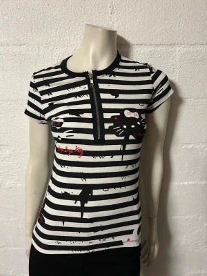 Topp med bye bye Kitty. Stl M/L. Från Rock metal. - Helt ny topp med jag tror det är bye bye Kitty. Lite stretchig bomullstrikå.