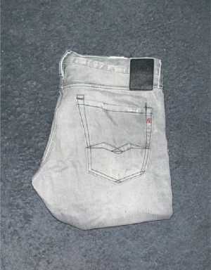 Replay Waitom jeans  - Snygga ljusgrå Replay Waitom jeans med klassisk femficksdesign och raka ben. Jeansen har svarta detaljer på bakfickorna och ett svart Replay-märke i midjan. Midja 46cm, längd 103cm. JAG SKICKAR EJ FLER BILDER NÄR JAG BÄR JEANSEN! för storleksguide hänvisar jag till måtten och för bättre inblick i passformen rekommenderar jag att googla på modellnamnet. Jeansen kan vara uppsydda utan att jag noterat det så kolla måtten noggrant :) 40