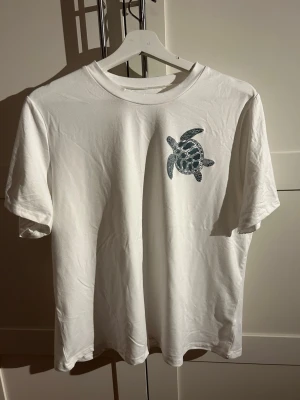 Vit t-shirt strl. XL - En clean t-shirt med endast en liten sköldpadda som tryck på framsidan. Inte mycket använd.