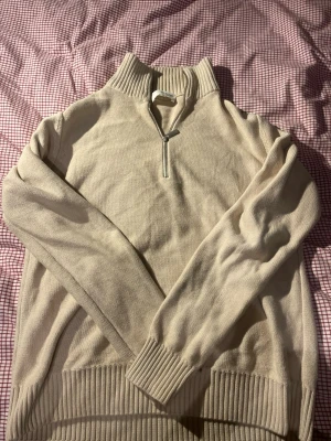 Beige stickad half zip-tröja - Snygg beige stickad tröja från H&M med ribbad krage och muddar. Tröjan har en half zip-dragkedja framtill och långärmad design. Perfekt för lager-på-lager och chill stil under höst och vinter.