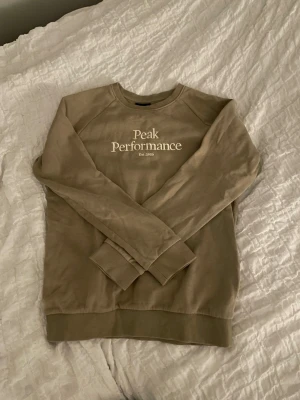 Peak Performance sweatshirt - Säljer en beige sweatshirt från Peak Performance som är i storlek 160 cm. Tröjan har använts varsamt och det finns inga synliga skador. Vid fler frågor och funderingar, tveka inte på att kontakta mig!