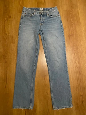 Ljusblå raka jeans - Säljer ett par klassiska ljusblå jeans med raka ben och normal passform. Jeansen har fem fickor, knapp och dragkedja framtill samt en enkel, tidlös look. Perfekta för dig som gillar en avslappnad stil.