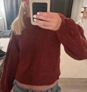 Mörkröd stickad tröja croppad - Mysig mörkröd stickad tröja med croppad passform och långa ärmar. Perfekt för att ge din outfit en chill vibe och funkar fett bra till jeans. Tröjan har ribbade muddar vid ärmslut och nederkant för extra stilpoäng.