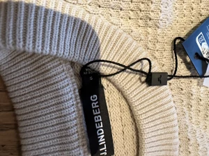 Beige stickad tröja från J.Lindeberg - Snygg beige stickad tröja från J.Lindeberg i storlek S. Tröjan har ett strukturerat mönster och ribbade muddar vid hals, ärmslut och nederkant. 