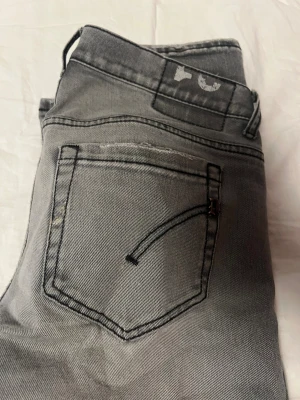 Jeans Dondup george - Snygga grå jeans från Replay med skinny passform och klassisk femficksdesign. Jeansen har svarta sömmar och en lätt tvättad look som ger en cool vibe. Perfekt för dig som gillar stilrena och moderna jeans med smal siluett. Lagade i skrevet men syns bara från insidan