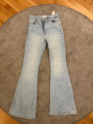 Ljusblå flare jeans från Bershka - Säljer ett par ljusblå flare jeans från Bershka i storlek 36. De har klassisk femficksdesign, medel midja och breda utsvängda ben. Jeansen är tillverkade i mjukt denim och har en snygg tvättad look som ger en cool retro vibe.