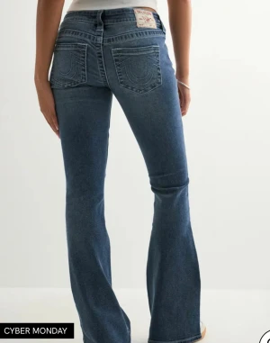 True Religion blå bootcut jeans - Säljer ett par blå jeans från True Religion med bootcut passform och låg midja. Jeansen har klassiska fickor med broderade detaljer bak och en tydlig logotyp på bakfickan. Materialet är jeans med snygg tvätt och silverfärgade knappar. Pris kan diskuteras 💗 aldrig använt dom dock har jag tagit bort lappen. 