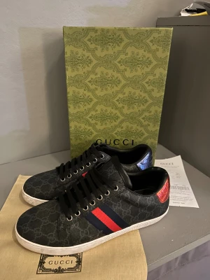 Gucci skor - Tja! Säljer mina Gucci sneakers i svart då jag behöver pengar. GG-monogram, röd och blå rand på sidan samt metallicröd och metallicblå häl med Gucci-logga. Riktigt stilrena och passar till mycket! Om du har några frågor fråga på😇
