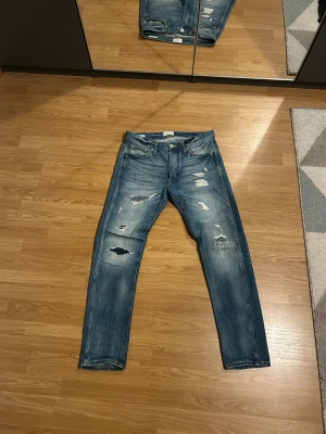 Jack & Jones jeans med slitningar - Riktigt snygga Jack & Jones jeans med supersnygga slitningar. Dessa har varit favoriter ett tag men jag kände nu att det var dags o sälja dem eftersom jag har fått nya jeans som ser för lika ut. Väldigt skön passform. Storlek 31/32. 