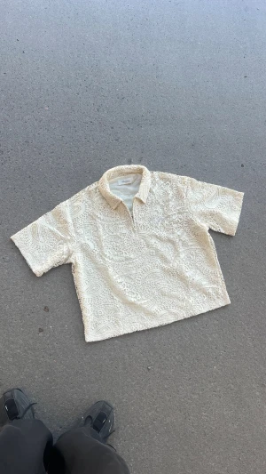 Dreamz| Beige styckad Quarter Zip Tröja - Skjortan har ett paisley-inspirerat spetsmönster som ger en riktigt clean och modern vibe. Materialet är lätt och luftigt, perfekt för varma dagar. Passformen är loose | Alla Storlekar från XS-XXL| skriv gärna din vikt och längd för din perfekta storlek| Org pris 499