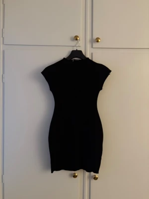 Svart kortklänning från Zara. Midiklänning, miniklänning, svart klänning figurnära tight  - Superfin klänning i nyskick. Endast använd 1 gång! Säljer en svart, figurnära kortklänning från Zara med hög hals och korta ärmar. 