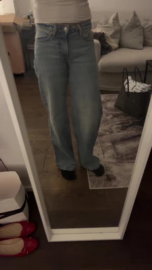 Blå wide jeans med hög midja - Säljer ett par ljusblå lågmidjade jeans och wide fit. Klassiska raka ben och knappgylf. Jeansen har en chill vibe och är perfekta för dig som gillar en avslappnad stil. Materialet är jeans.💕 helt nya men lappen råkade åka av..💕