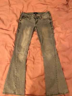 True Religion ljusblå bootcut jeans - Säljer ett par ljusblå bootcut jeans från True Religion med klassiska kontrastsömmar och broderad ficka bak. Jeansen har låg midja, fem fickor och är tillverkade i denim med snygg tvätt. Perfekta för dig som gillar retrovibbar och vill sticka ut. Har vanligtvis 25-26w men kan ha dessa med! Använda fåtal gånger så är som nya💕