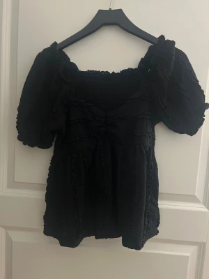 Svart blus med volang och puffärm - Säljer en svart blus med puffiga korta ärmar i strl s