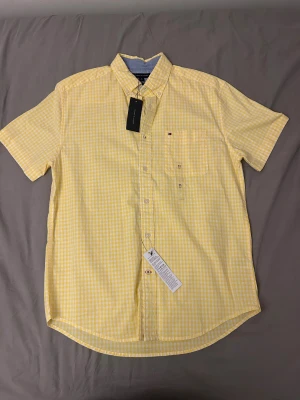 Tommy Hilfiger skjorta - Gul kortärmad skjorta från Tommy Hilfiger.  Ny och aldrig använd med prislappen kvar. Storlek M 98% Bomull