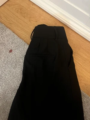 Svarta kostymbyxor shorts från Zara går att diskutera pris - Svarta kostymbyxor från Zara med hög midja och klassisk rak passform. Byxorna har hällor för bälte, diskreta fickor och är tillverkade i ett mjukt tyg som ger en dressad look. Perfekta för en stilren outfit.