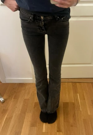 Mörkgråa Bootcut jeans Gina tricot  - Säljer ett par svarta bootcut jeans från Gina Tricot i storlek 32. Modellen har låg midja, klassiska fem ficko. Jeansen är i stretchigt denim och har en snygg tvättad look. Jag har sprättat ner jeansen! Lite kort för mig som är 174cm💗