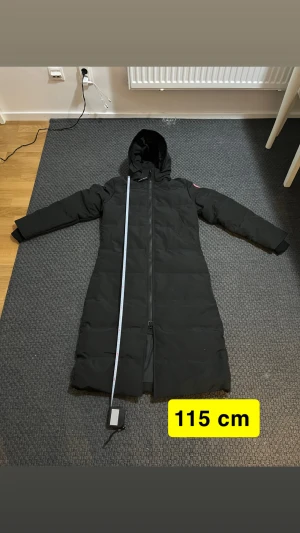 Svart lång dunjacka Canada Goose L  (Perfekt M) - Här är en varm och vattentät Canada-jacka, perfekt för vintern. Designad för att klara kyla, snö och regn – håller dig både torr och riktigt varm. Snygg passform och bra kvalitet.