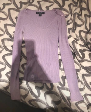 Slim fit ljuslila ribbad tröja från Amisu - Supersnygg ljuslila ribbad tröja från Amisu med v-ringning och långa ärmar. Tröjan är figurnära och har en mjuk, stretchig känsla som passar perfekt till jeans eller kjol. Enkel men ändå trendig, perfekt för dig som gillar stilrena plagg.