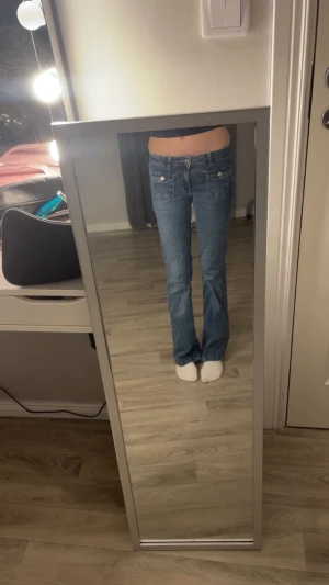 Blå bootcut jeans från Kappahl - Säljer ett par blå bootcut jeans från Kappahl i storlek 152. Jeansen har låg midja, klassiska fickor fram och bak samt snyggt utsvängda ben. Perfekta för dig som gillar en retro vibe och vill ha ett par jeans med skön passform.