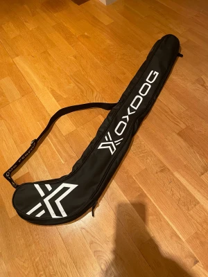 Svart Oxdog innebandyfodral med axelrem - Säljer ett Oxdog innebandyklubba fodral för väldigt billigt, säljer den eftersom jag spelar inte innebandy längre. Kom DM om ni vill ha fler detaljer.