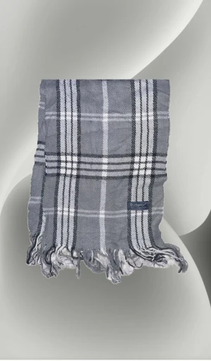 Grå rutig halsduk från Burberrys - Snygg grå halsduk från Burberrys med klassiskt rutigt mönster i vitt och svart. Gjord av 100% lammull, mjuk och varm med fransar i ändarna. Perfekt att slänga över axlarna för en cool och tidlös look.
