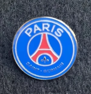 PSG pin i blått och rött - Snygg rund pin med Paris Saint-Germain-loggan i blått, rött och vitt. Perfekt för dig som älskar fotboll och vill visa vilket lag du supportar. Ikonisk design med Eiffeltornet i mitten och texten 'PARIS SAINT-GERMAIN' runt om.