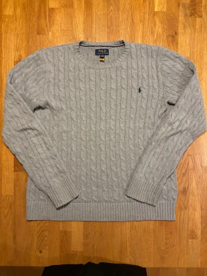 Grå kabelstickad tröja Polo Ralph Lauren - Tjena, säljer min mycket sparsamt använda kabelstickade tröja från ralph lauren. Tröjan sitter som ett mellanting mellan L och M. Pris kan diskuteras. Tveka inte att ställa några frågor eller skicka in pris förslag💯🔥 Snygg grå kabelstickad tröja från Polo Ralph Lauren med klassisk rund hals och broderad logga på bröstet. Tröjan har långa ärmar och ribbade muddar vid ärmslut och nederkant. Perfekt för dig som gillar stilren och tidlös design.