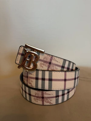 Burberry bälte vändbart silver logga  - Vändbart bälte från Burberry: svart på ena sidan, beige med klassiskt mönster påå andra. Fint skick, skickas samma dag.✅ hör av dig om du har några frågor, 125cm