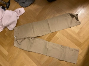 Beige/brun kostymbyxa - Kostymbyxor som sitter perfekt men som jag tyvärr aldrig får användning för. Jag är 165 och byxorna är perfekt för mig men lite längre i benen då jag inte gillar när de är för korta. Bootcut och väldigt snygga,sitter tajt över bakdelen med utsvängda byxben. Absolut inga tecken på användning då jag bara använt dom 1 gång.