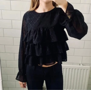 Glittrig volangblus - Jätte gullig svart blus med flera volanger & små glitterprickar. Endast använd 2-3 gånger 💗 (storlek 158/164 men sitter som XS) Perfekt till nyår
