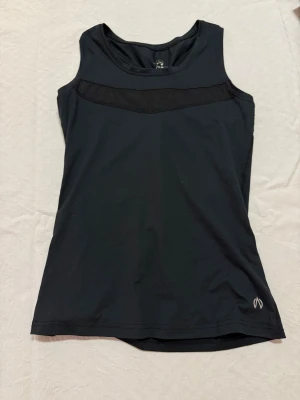 Svart linnetopp från North Bend - Sportig svart linnetopp från North Bend med meshdetalj över bröstet och snyggt brottarrygg med rosa och svart mönstrad knyt. Toppen har en stilren logga framtill och är tillverkad i mjuk polyester som andas. Perfekt för träning och aktiva dagar.