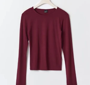 Vinröd långärmad tröja  - Snygg vinröd långärmad tröja från Gina med rund halsringning och enkel, stilren design. Materialet är mjukt och skönt mot huden.