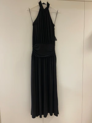 Svart långklänning med öppen rygg - Svart långklänning från ginatricot med halterneck. Klänningen har endast testats så lapp kvar